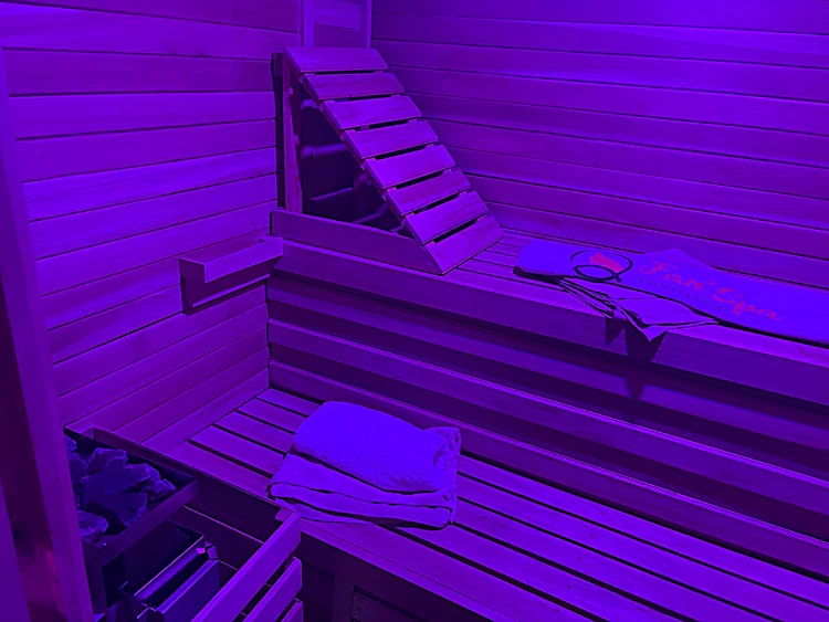Sauna de madera iluminado con luz morada de cromoterapia